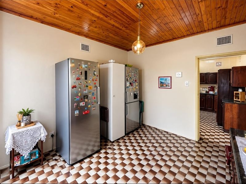 Kitchen area featuring a timber ceiling, checkered floor tiles, and a doorway leading to an adjacent scullery or secondary kitchen space.