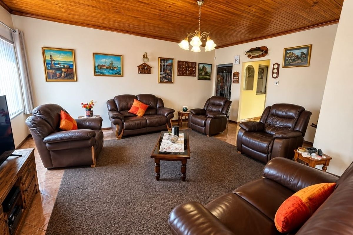 Spacious living room featuring a warm timber-clad ceiling, tiled flooring, and an open archway leading to adjacent areas.