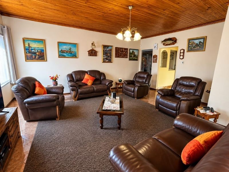 Spacious living room featuring a warm timber-clad ceiling, tiled flooring, and an open archway leading to adjacent areas.