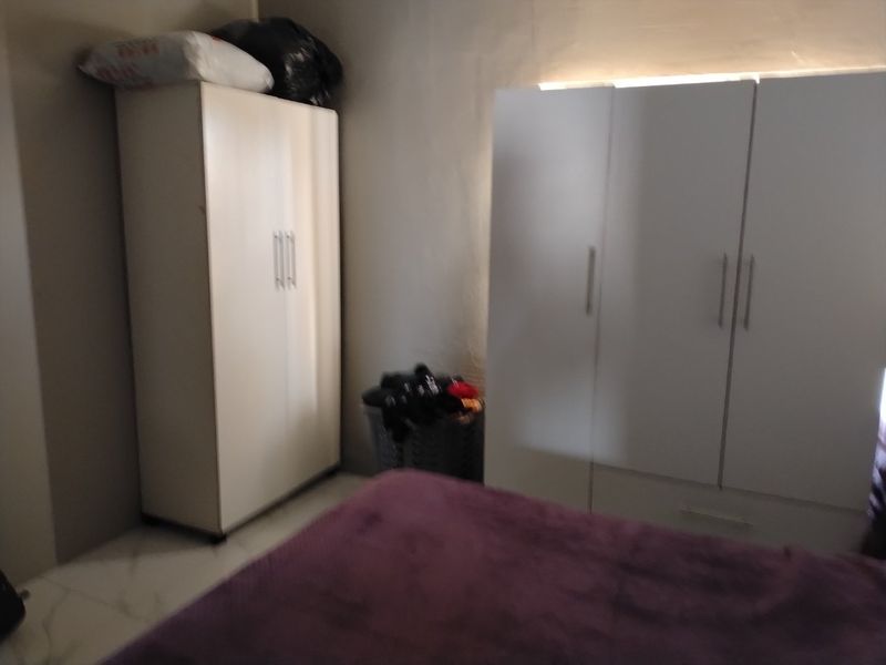 A bedroom featuring tiled flooring and built-in storage cabinetry.