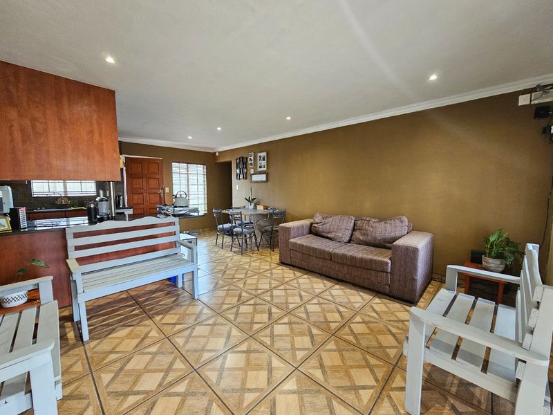 Open-plan living and kitchen area featuring tiled flooring, recessed lighting, and functional kitchen cabinetry in a townhouse setting.