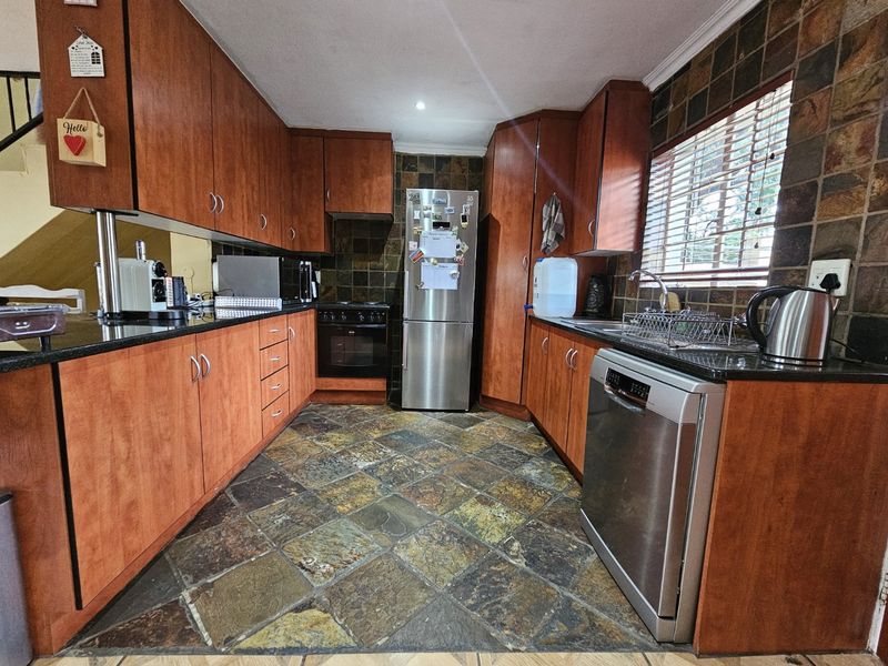 A functional kitchen featuring warm-toned wooden cabinetry, granite countertops, slate tile flooring, and a tiled backsplash, offering a classic and durable workspace.