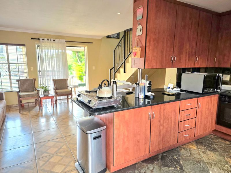 Open-plan kitchen and living area featuring granite countertops, wood-finish cabinetry, and direct access to an outdoor patio through sliding glass doors.