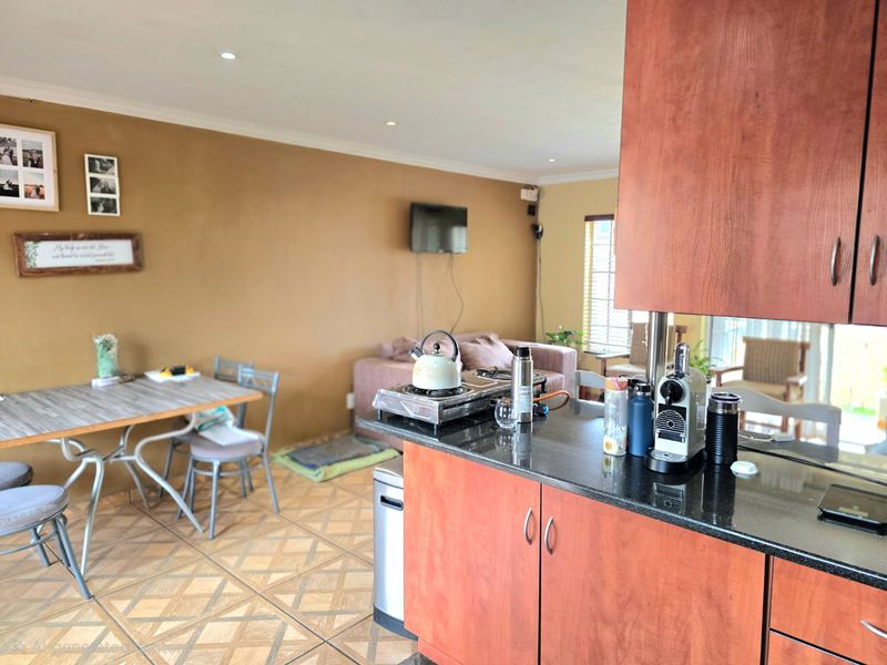 Open-plan living and kitchen area featuring granite countertops, wood-finish cabinetry, and tiled flooring, creating a functional combined space.