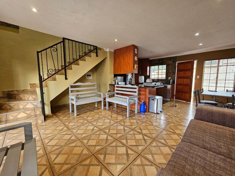 Open plan living and kitchen area featuring tiled flooring, a wrought iron staircase, and built-in cabinetry, offering a functional layout for daily living.