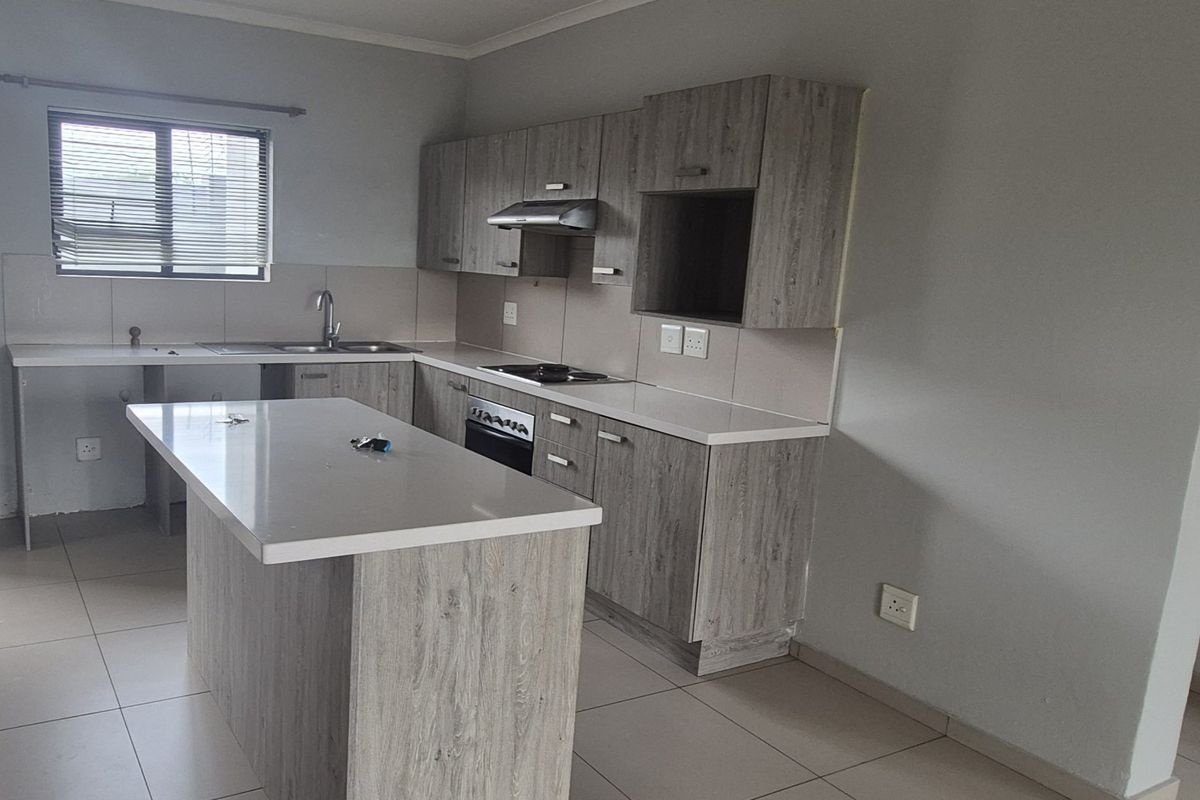 Modern kitchen featuring light wood-grain cabinetry, stone countertops, a central island, and built-in appliances, offering a clean and functional workspace.
