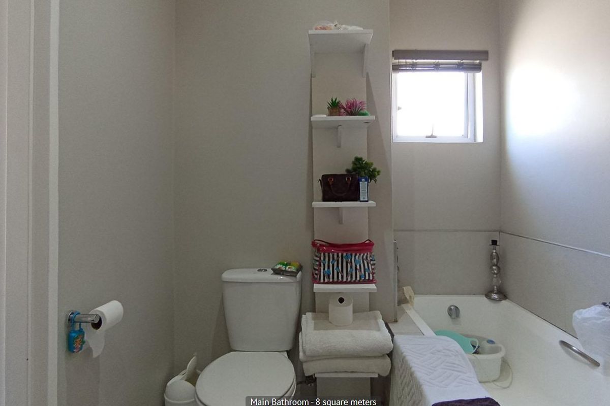 A functional bathroom featuring a standard bathtub, toilet, and built-in wall shelving, providing essential amenities for the apartment.