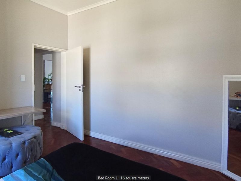 A bedroom featuring classic parquet flooring, neutral wall finishes, and coving, providing a clean and functional space.
