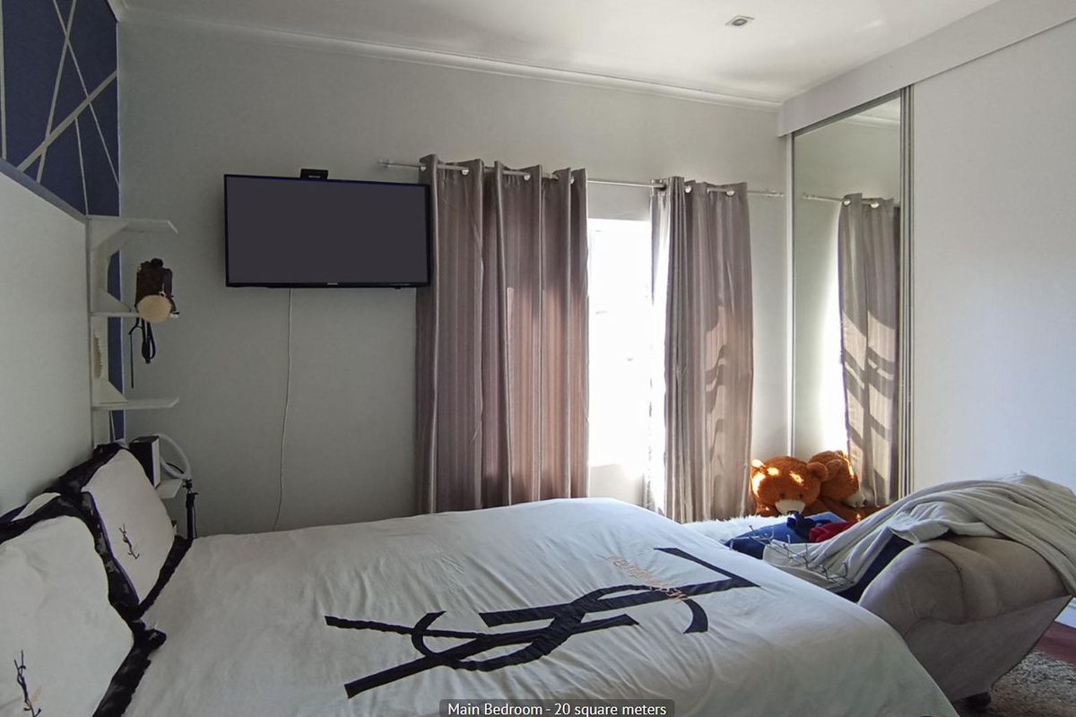A bedroom featuring a mirrored sliding wardrobe and recessed ceiling lighting, providing functional storage and a neutral aesthetic.