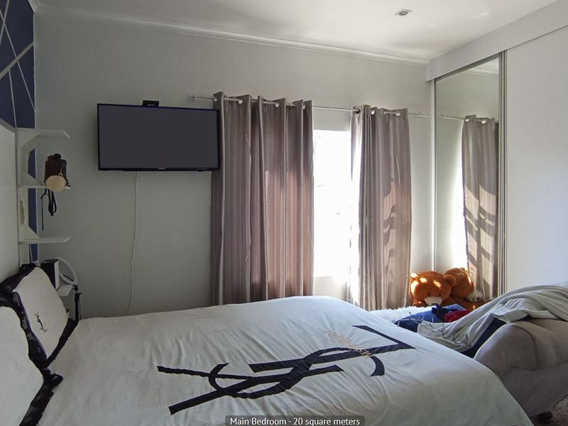 A bedroom featuring a mirrored sliding wardrobe and recessed ceiling lighting, providing functional storage and a neutral aesthetic.