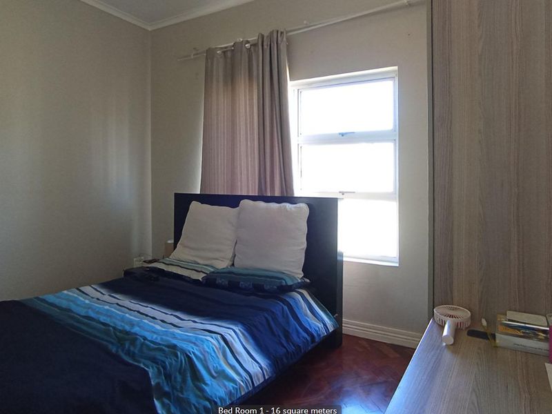A bedroom featuring parquet flooring and a built-in wardrobe, with a floor plan overlay included in the image.