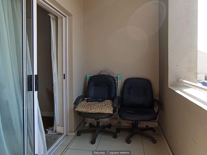 A compact balcony featuring tiled flooring and a metal balustrade, accessible via a sliding glass door from the interior living space.