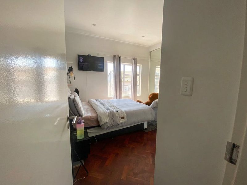 A bedroom featuring classic parquet flooring, recessed ceiling lighting, and a built-in sliding door wardrobe, viewed from the doorway.