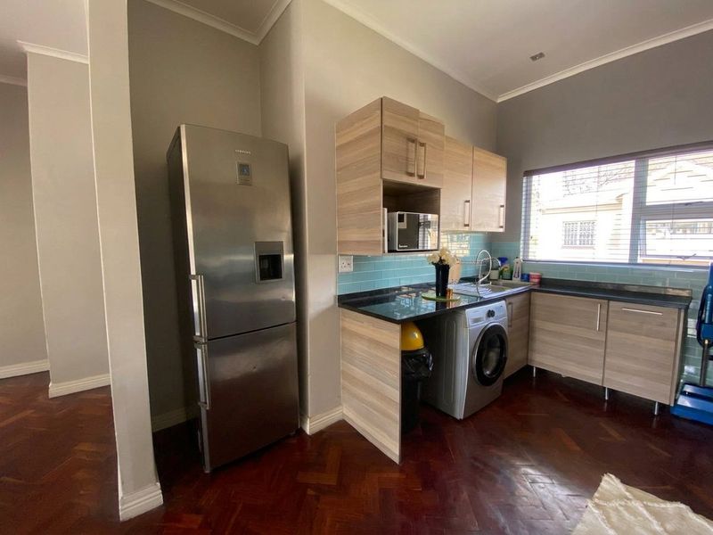 A functional kitchen featuring light wood-tone cabinetry, dark granite countertops, a blue subway tile backsplash, and classic parquet flooring.