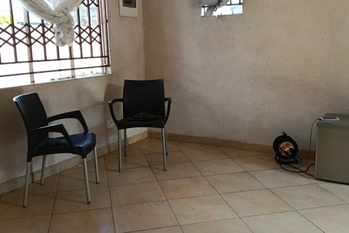 A sparsely furnished living area featuring tiled flooring and security bars on the windows, offering a blank canvas for potential interior updates.