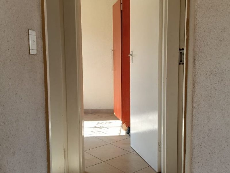 A functional hallway featuring tiled flooring and access to adjacent rooms with built-in storage cabinetry.