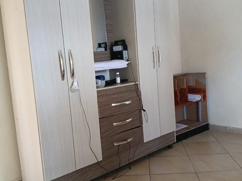 A bedroom featuring tiled flooring and a large built-in wardrobe with integrated drawers and shelving.