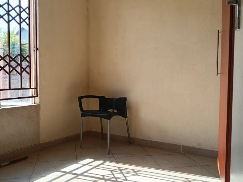 A vacant bedroom featuring tiled flooring and a window fitted with a security gate, offering a blank canvas for potential interior design updates.