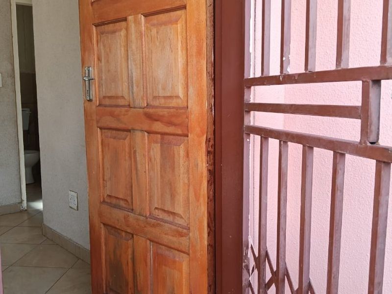 Entryway featuring a solid wood door, metal security gate, and ceramic tiled flooring.