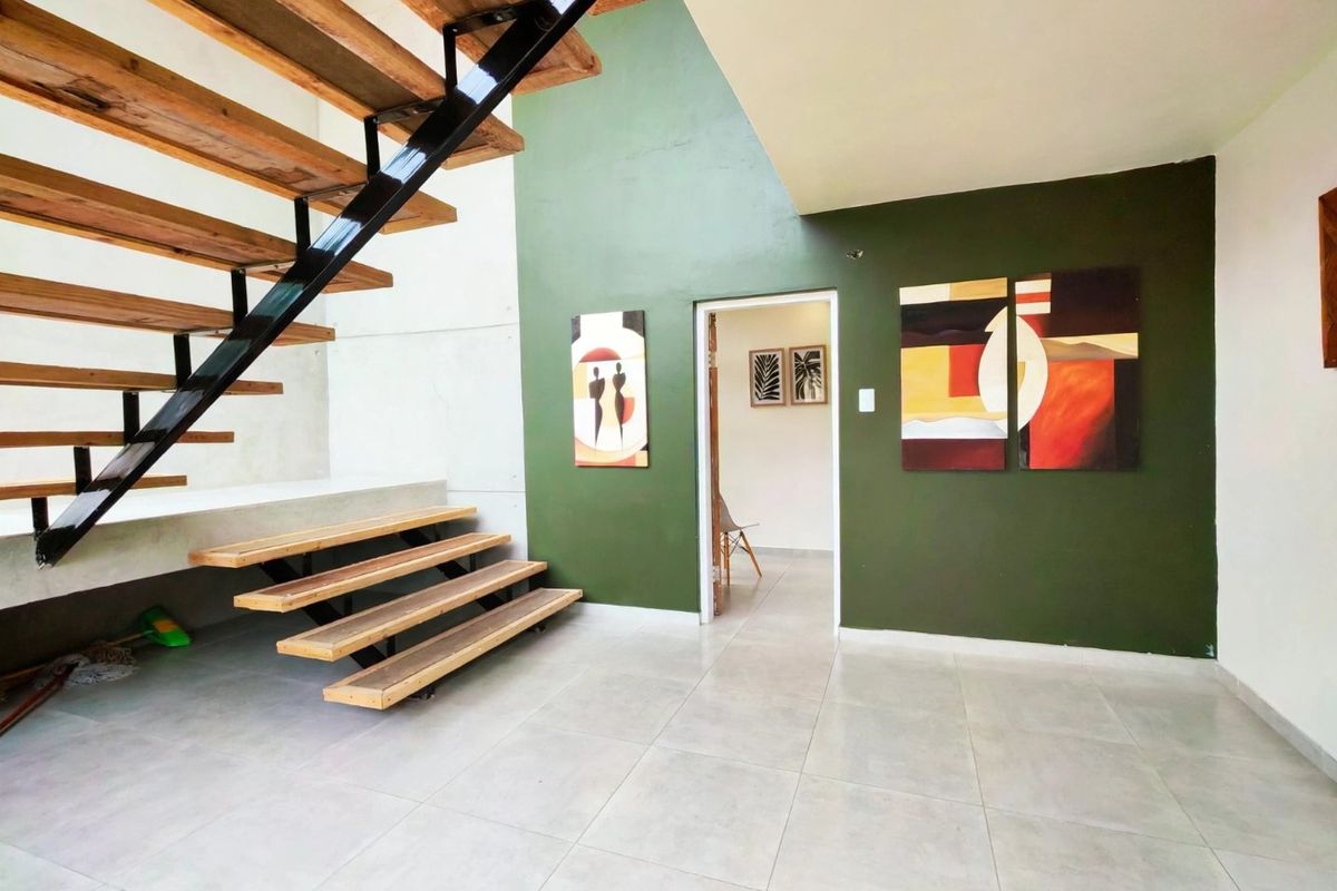 Spacious living area featuring a modern open-tread staircase with steel framing and large format floor tiles.