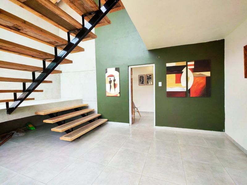 Spacious living area featuring a modern open-tread staircase with steel framing and large format floor tiles.