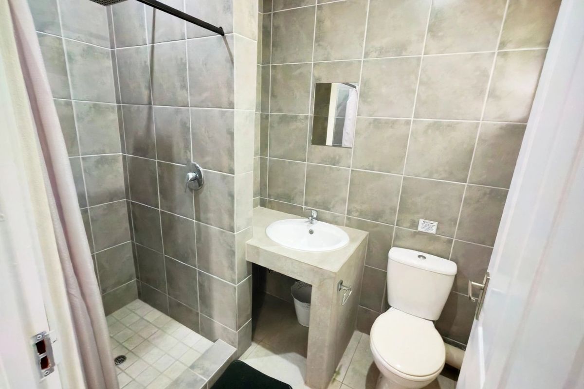 A modern bathroom featuring a walk-in shower with a rain shower head, a built-in vanity with a ceramic basin, and a standard toilet.