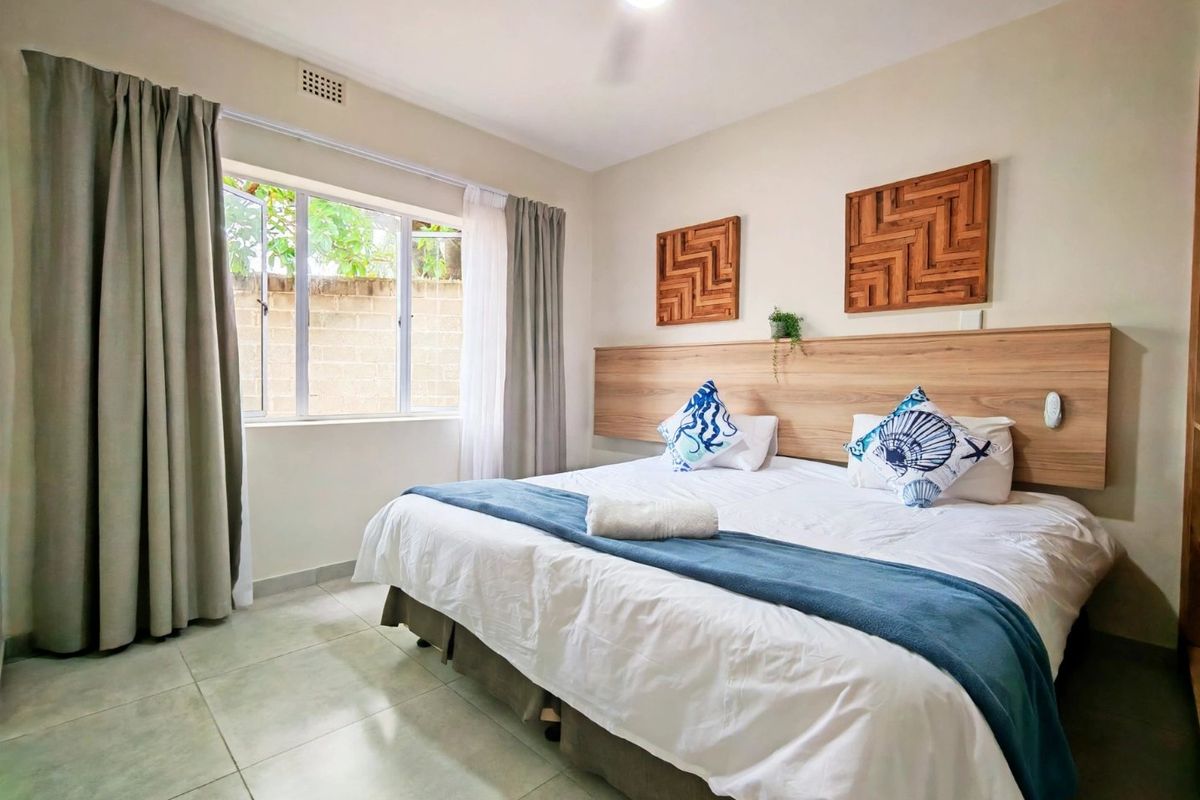 A well-maintained bedroom featuring tiled flooring, a built-in wooden headboard, and a ceiling fan, providing a comfortable and functional sleeping space.