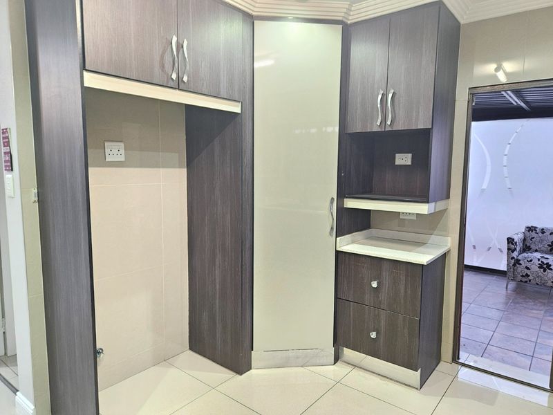 A modern kitchen corner featuring dark wood-grain cabinetry, a light-colored stone countertop, and tiled flooring, providing a clean and functional storage area.