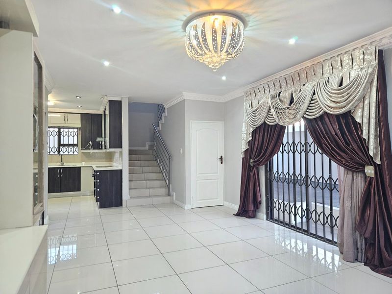 Spacious open-plan living area featuring polished tile floors, a modern kitchen, and a staircase, offering a bright and versatile layout for comfortable living.