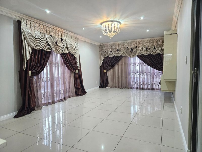 Spacious living area featuring polished porcelain floor tiles, recessed downlighting, decorative ceiling cornices, and secure sliding doors with integrated security gates.