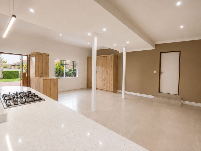 Spacious open-plan living area featuring a modern kitchen with stone countertops, gas hob, built-in cabinetry, and neutral tiled flooring throughout.