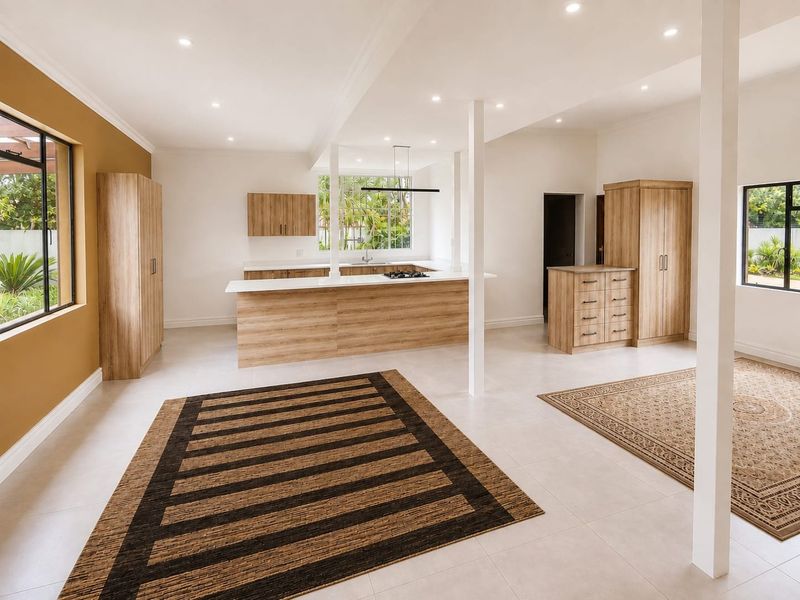 Spacious open-plan living and kitchen area featuring modern wood-finish cabinetry, a central island with a gas cooktop, and bright, neutral tiled flooring.