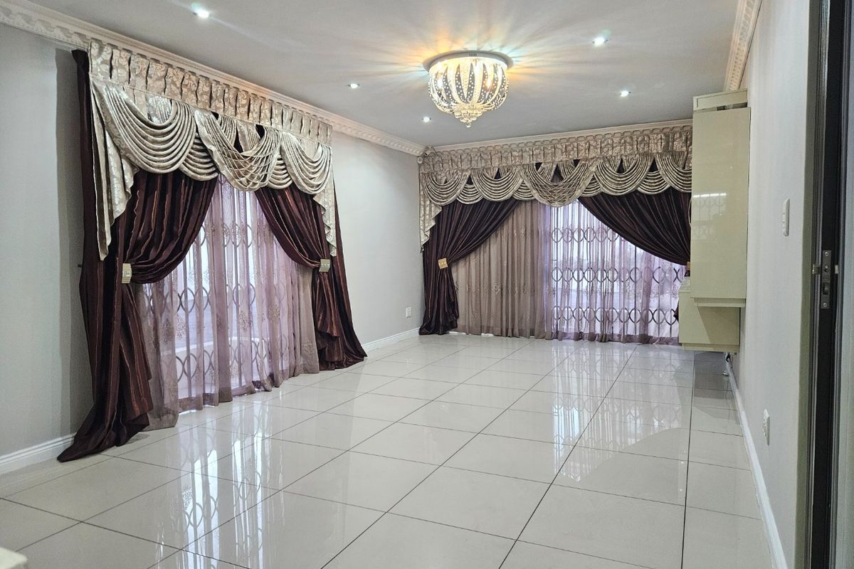 Spacious living area featuring polished porcelain floor tiles, recessed downlighting, decorative ceiling cornices, and secure sliding doors with integrated security gates.
