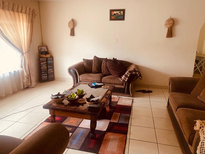 A comfortable living room featuring neutral tiled flooring and natural light from the window, providing a functional space for relaxation.