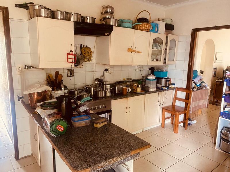A functional kitchen featuring built-in cabinetry, granite countertops, a tiled backsplash, and a freestanding stove, offering potential for modernization and improved storage layout.