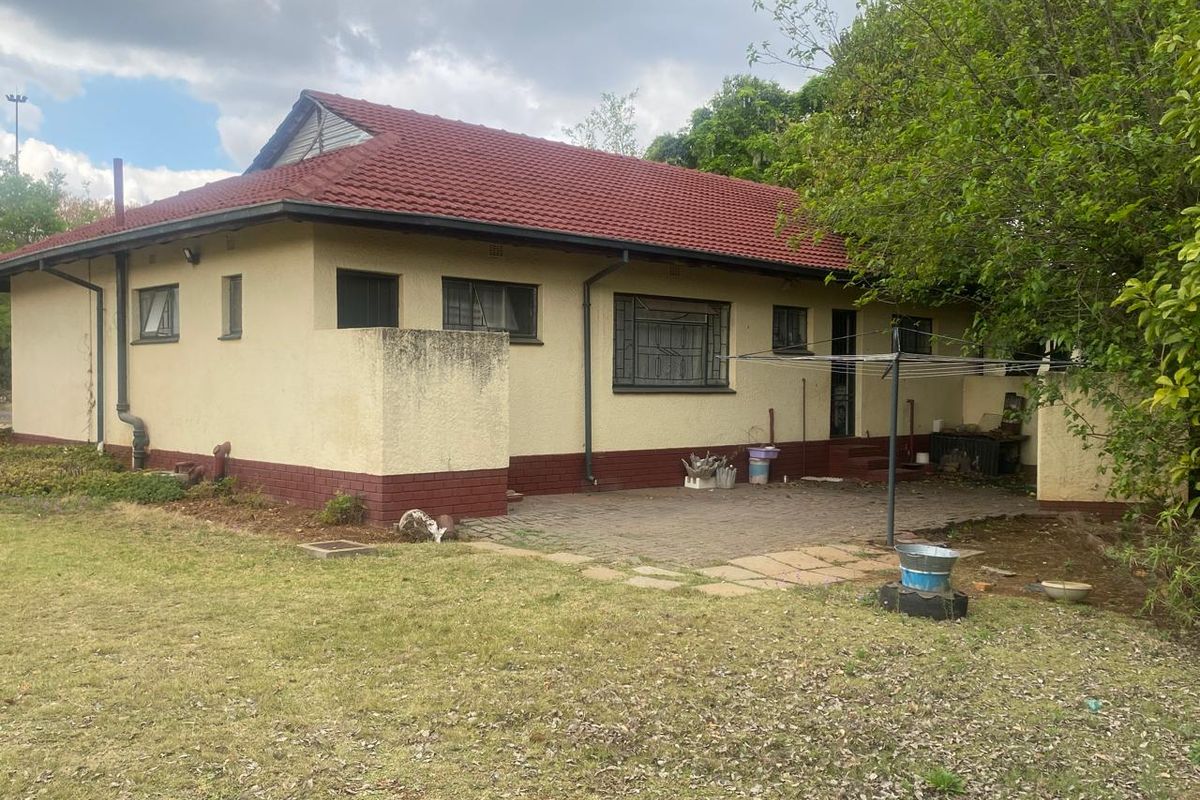 Rear view of the house featuring a tiled roof, paved patio area, and security bars on the windows.
