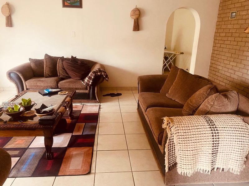 A living room featuring ceramic floor tiles, a brick feature wall, and an arched doorway leading to an adjacent space.