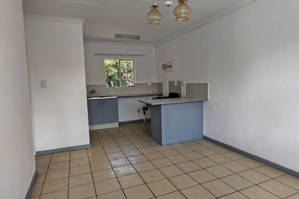 An empty, functional kitchen featuring tiled flooring, built-in cabinetry, and a breakfast counter, offering a blank canvas for potential renovation and modernization.