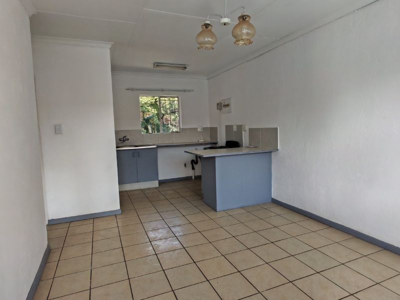 An empty, functional kitchen featuring tiled flooring, built-in cabinetry, and a breakfast counter, offering a blank canvas for potential renovation and modernization.