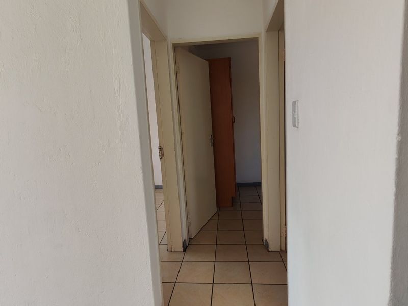 A functional hallway featuring tiled flooring and access to multiple rooms, providing a clean and neutral transition space within the apartment.