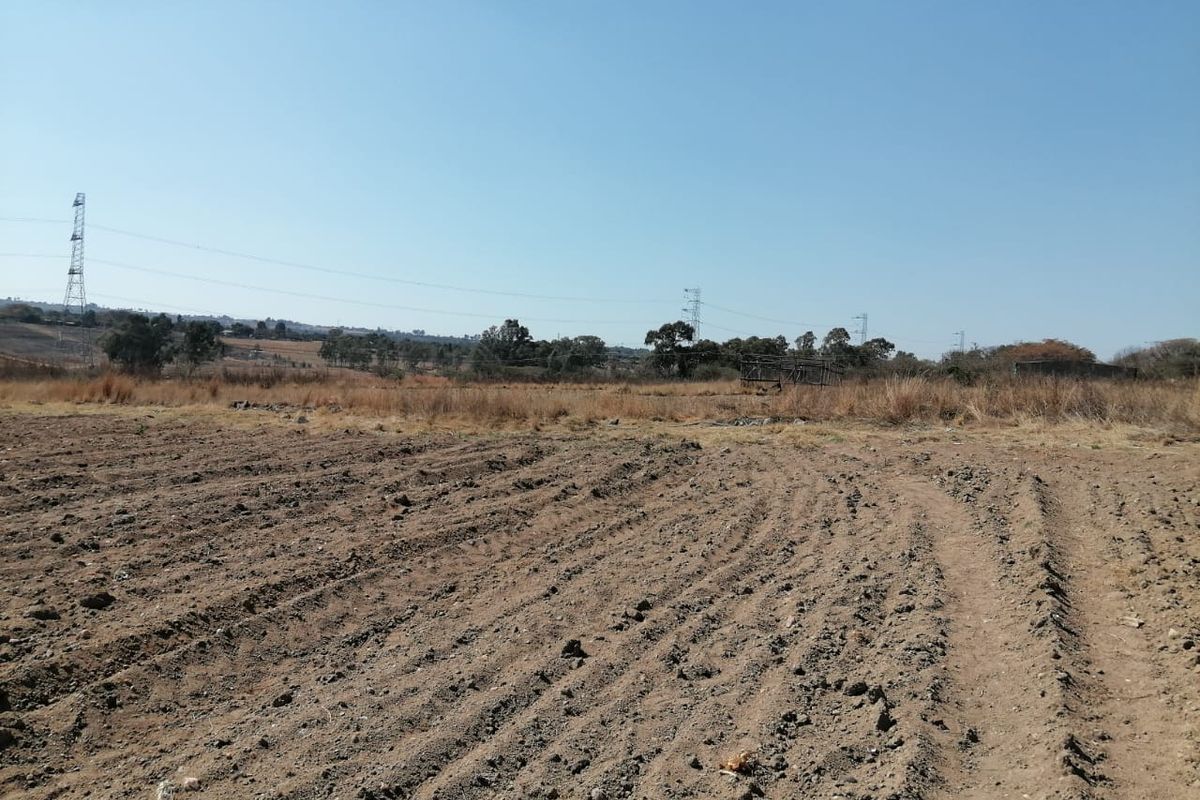 A wide-angle view of a vacant residential plot featuring cleared soil and open landscape, suitable for future development.