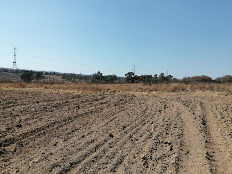 A wide-angle view of a vacant residential plot featuring cleared soil and open landscape, suitable for future development.