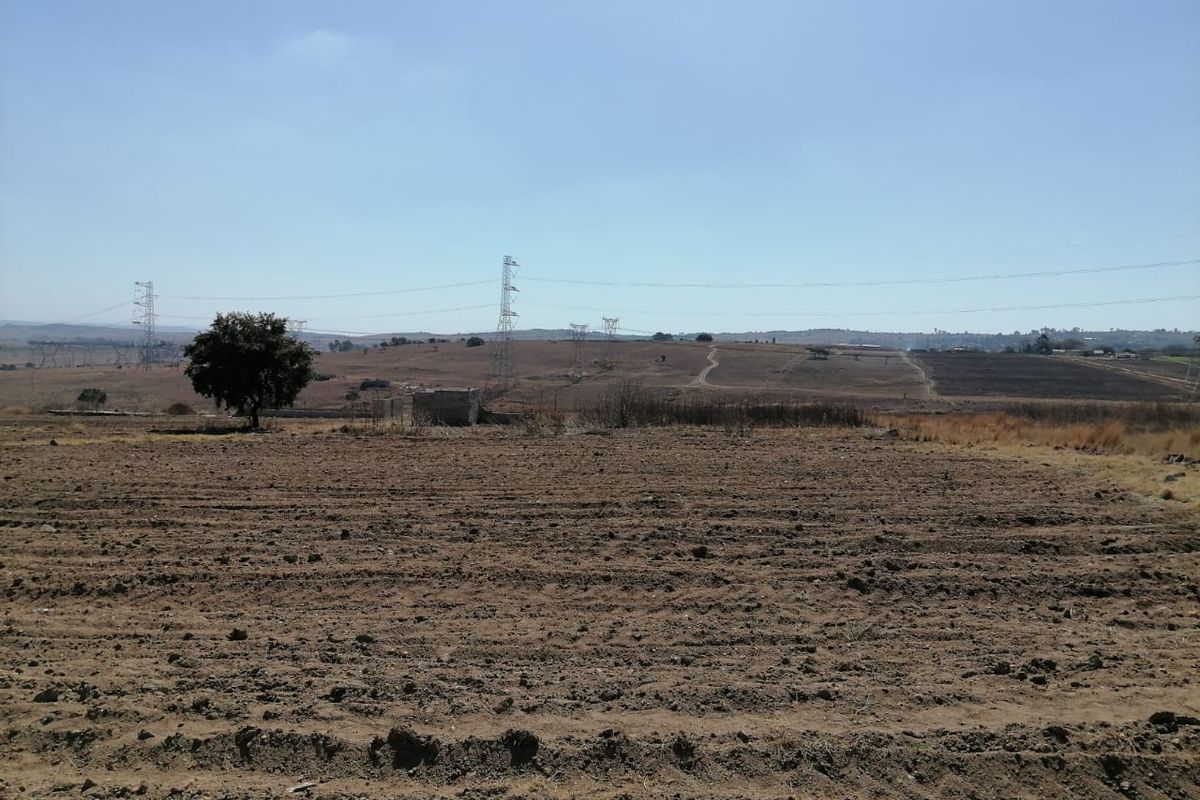 A wide-angle view of open, undeveloped residential land featuring distant high-voltage power lines and natural terrain.