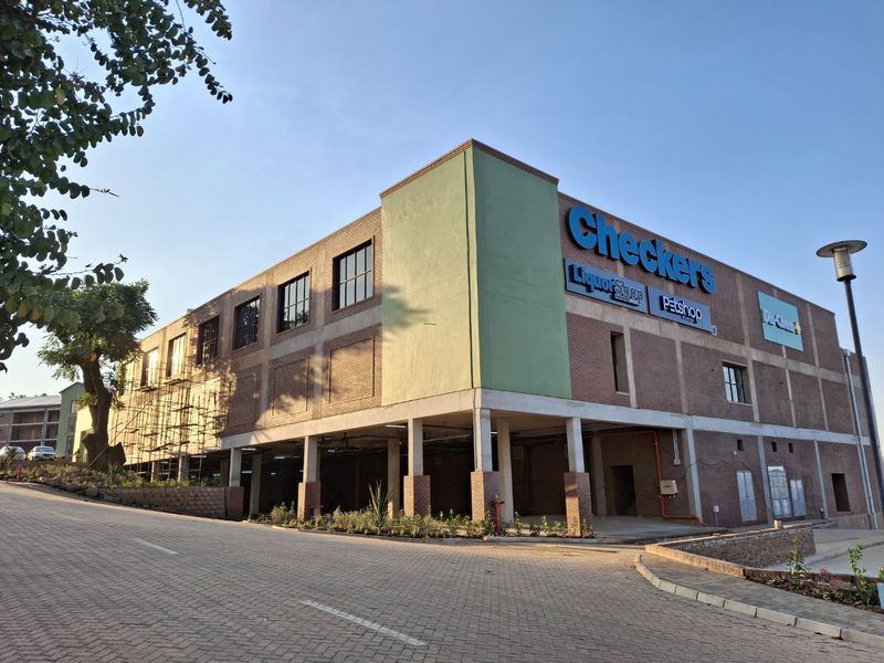 Exterior view of a commercial apartment building complex featuring a brick facade, covered parking area, and prominent retail signage.