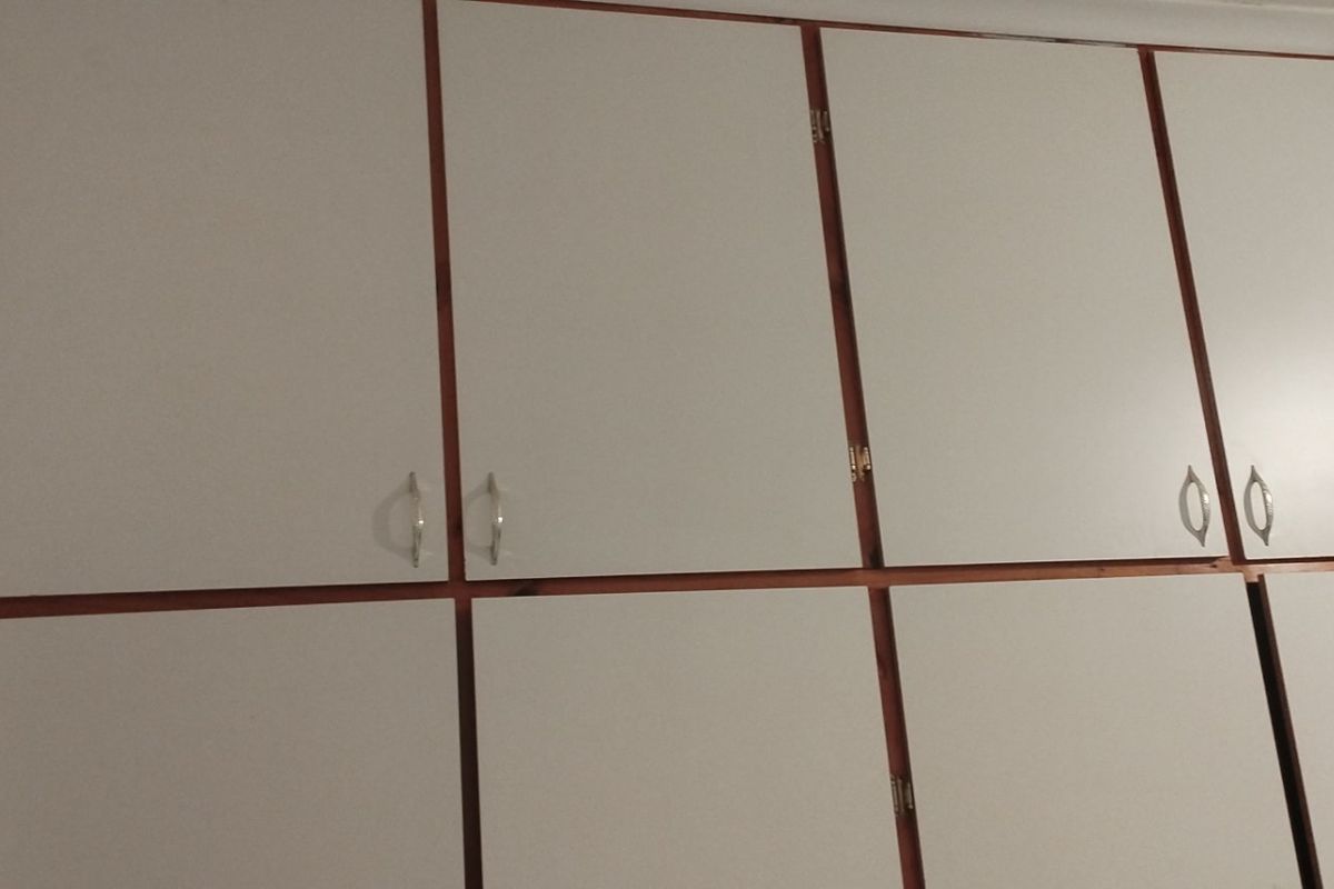 A view of built-in bedroom cupboards with white doors and wooden trim.