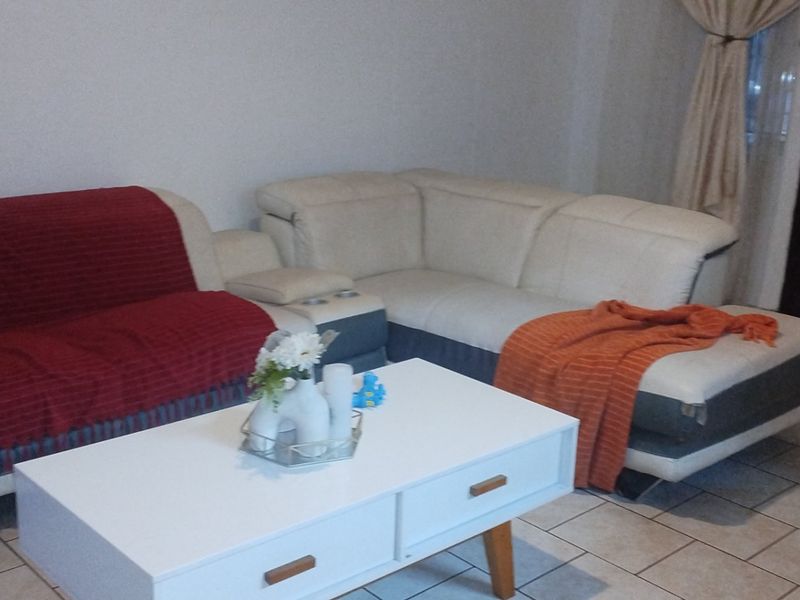 A living room area featuring tiled flooring and a timber entrance door, providing a functional space for relaxation.