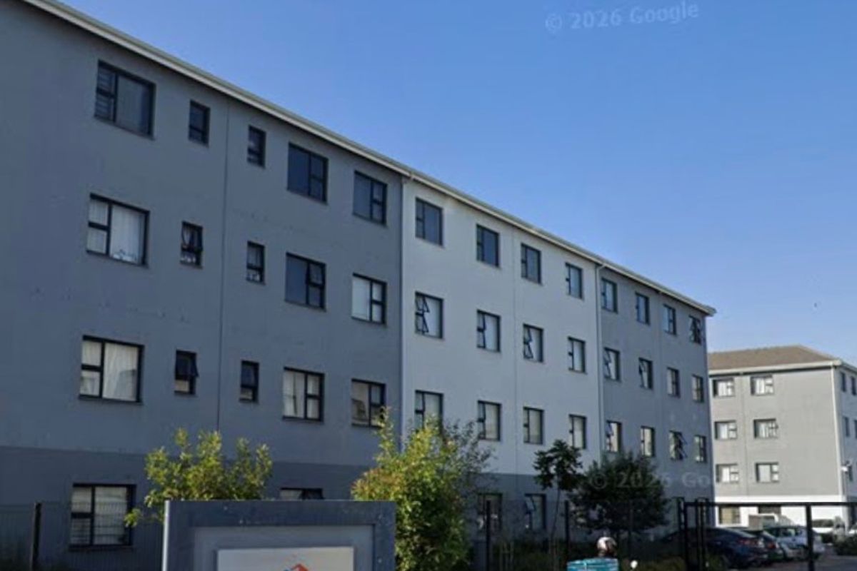 Exterior view of the Belhar Views apartment complex, featuring a paved entrance, security gate, and modern multi-story residential building facade.