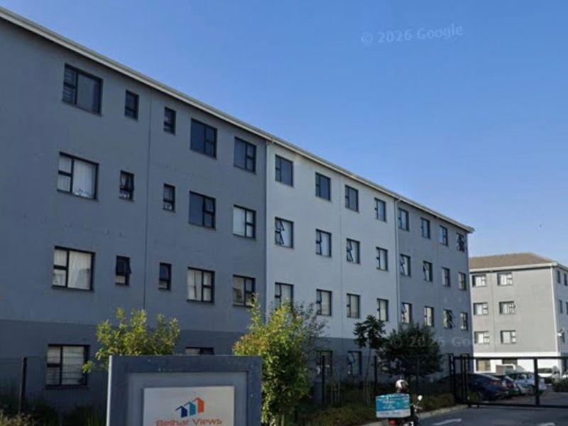 Exterior view of the Belhar Views apartment complex, featuring a paved entrance, security gate, and modern multi-story residential building facade.