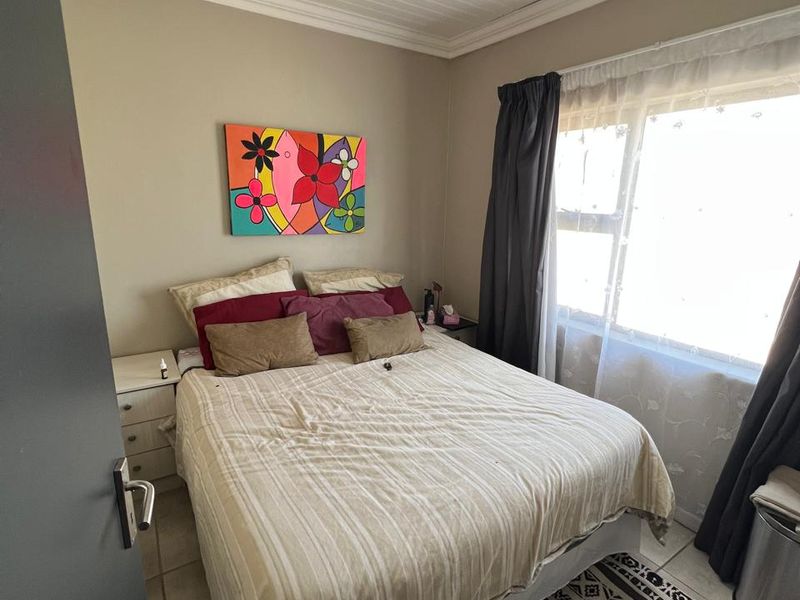 A cozy bedroom featuring tiled flooring and a classic tongue and groove ceiling, providing a functional and comfortable living space.