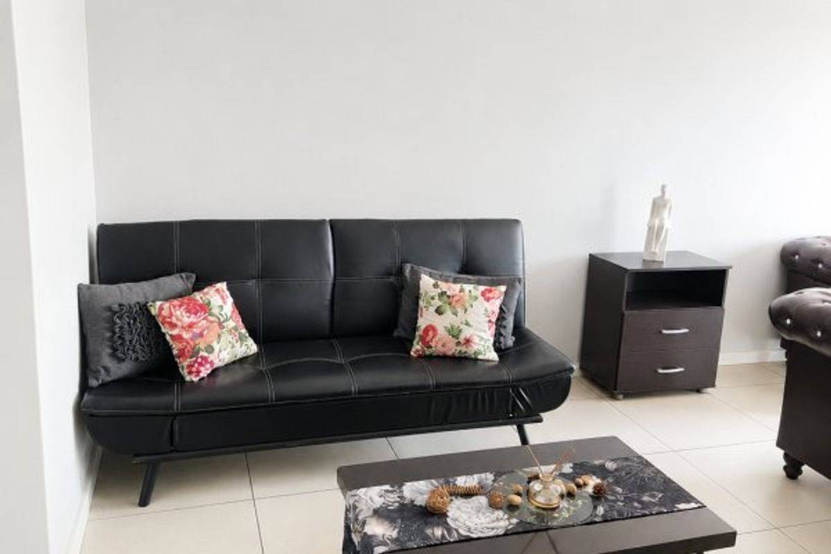 A bright living room area featuring neutral tiled flooring and a clean, minimalist aesthetic with coved ceiling detailing.